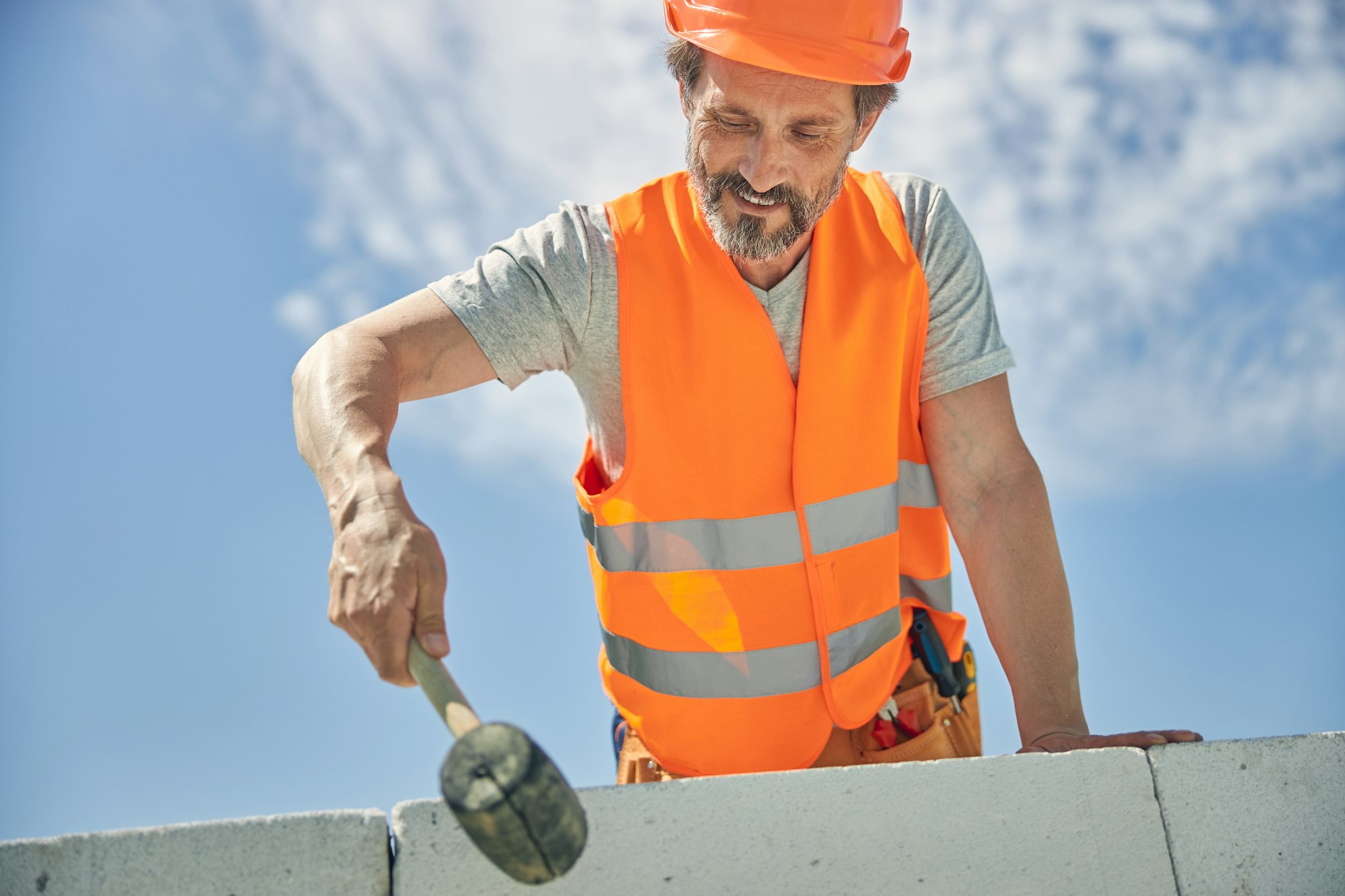 Skilled Caucasian bricklayer working with a hammer